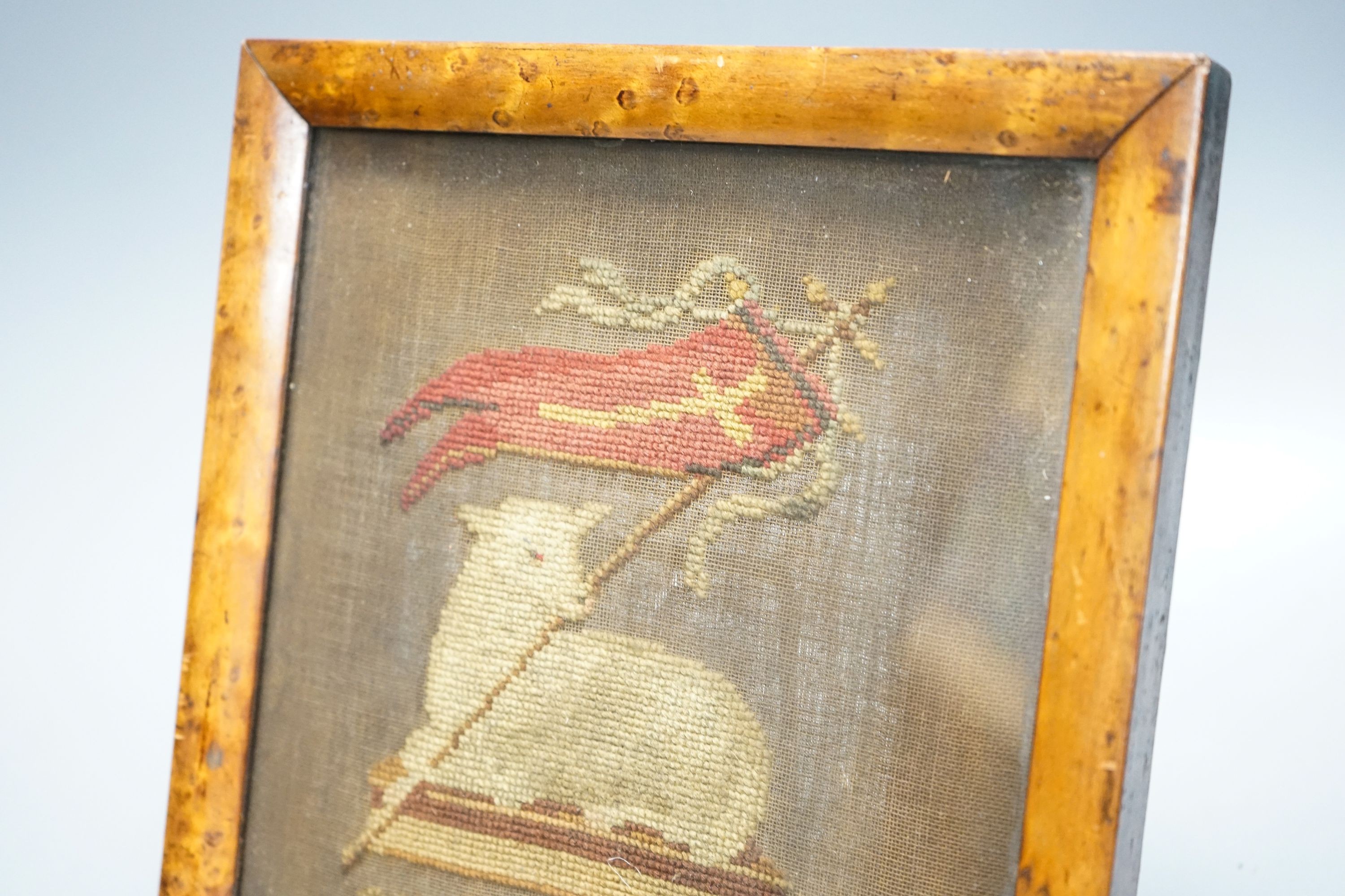 An early 19th century needlework of the Agnus Dei with the vexillum, incorporating a lamb and flag, in bird's eye maple frame 25x23cm incl frame